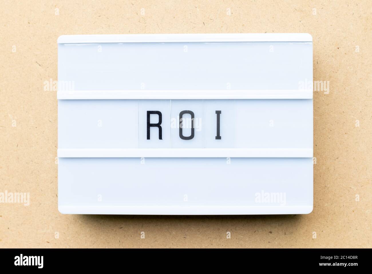 White lightbox with word ROI (Abbbreviation of Return on Investment) on wood background Stock Photo