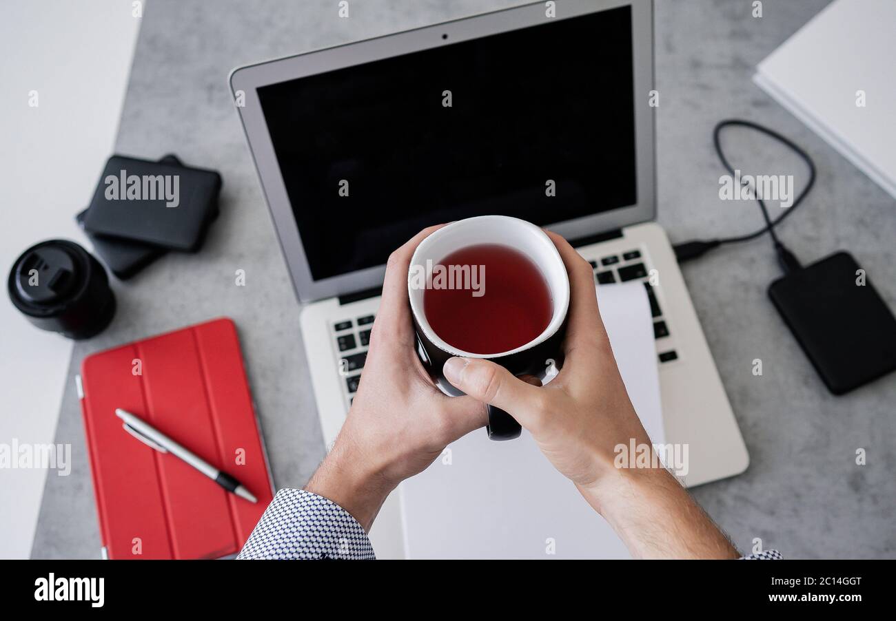Top view of man is working remotely at home, workplace - laptop, tablet pc, smart phone and cup of tea. Home office Stock Photo