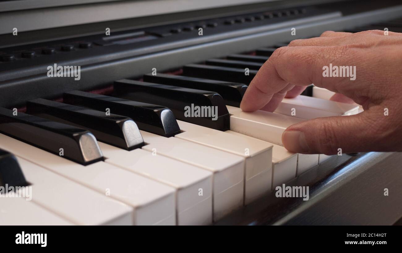 Close up of a pianist's right hand is playing on a digital piano with white and black keys Stock Photo