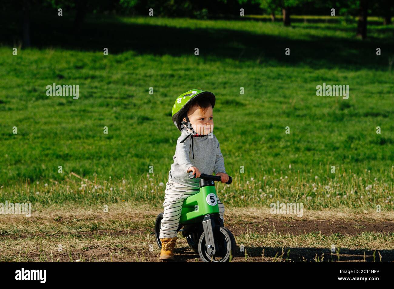 Grumpy little kid foot riding on a three-wheel bike Stock Photo - Alamy