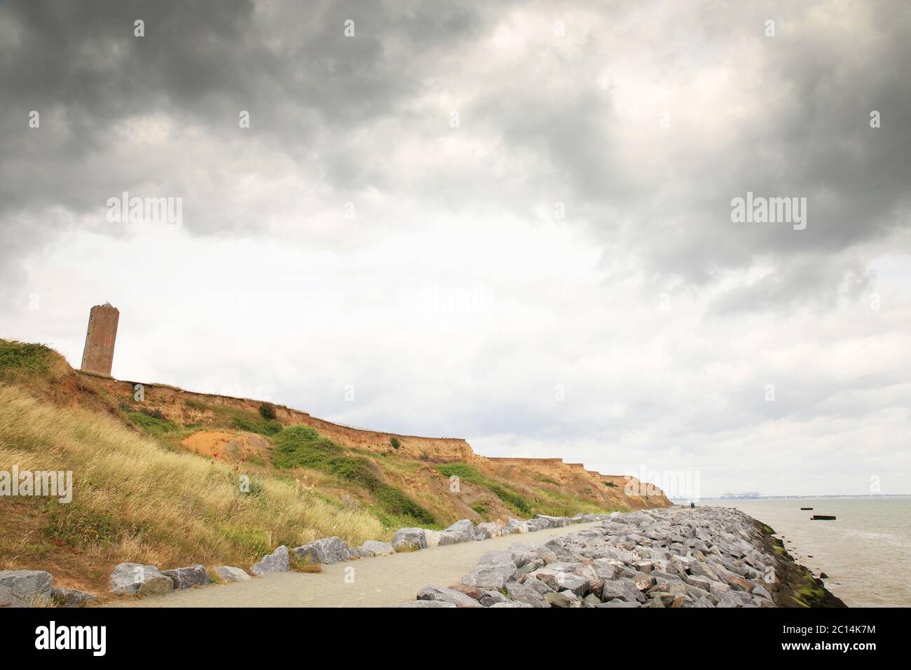 sea wall pathway defence along the seafront with the naze tower in the background Stock Photo