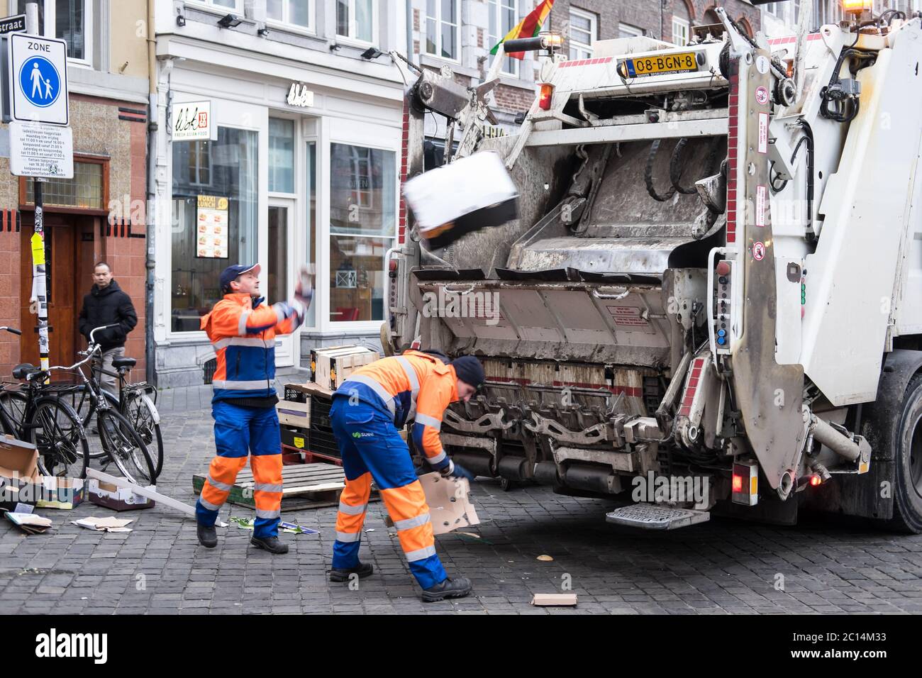 Garbage collectors throw waste from the market in a garbage truck on
