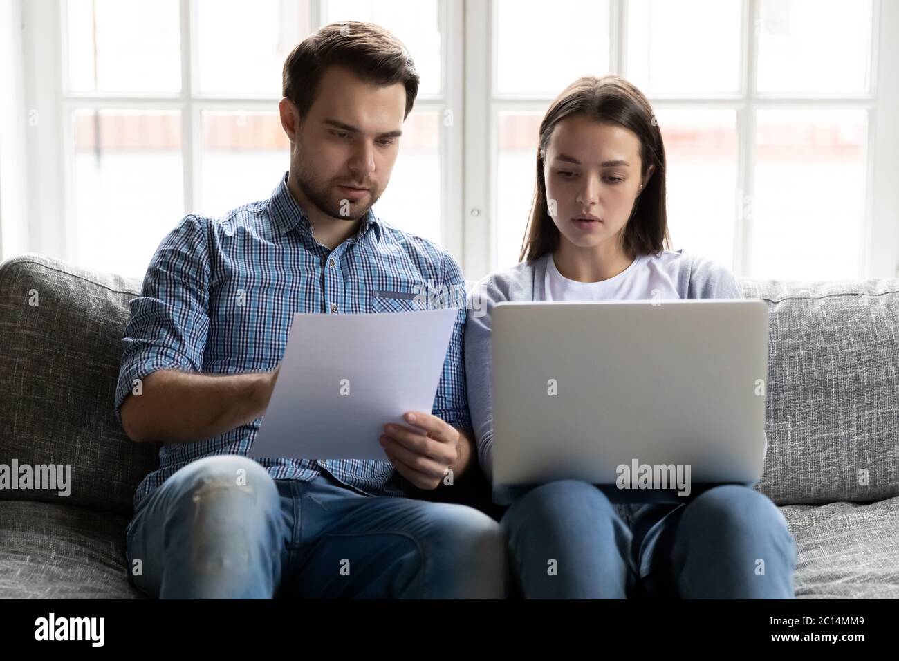 Serious young couple checking financial documents, using online banking service Stock Photo