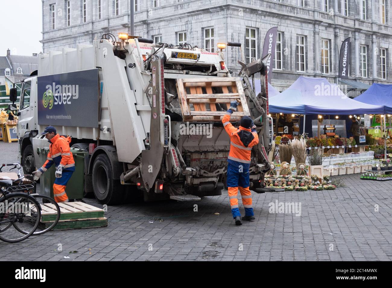 Garbage collectors throw waste from the market in a garbage truck on