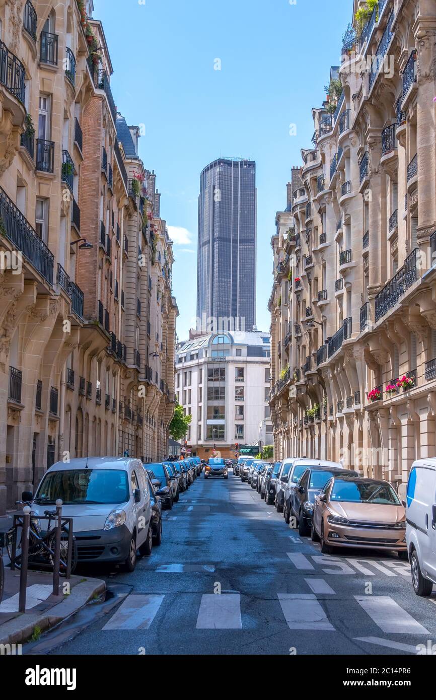 France. Montparnasse Tower at the end of a narrow Parisian street. Sunny summer day. Lots of parked cars Stock Photo