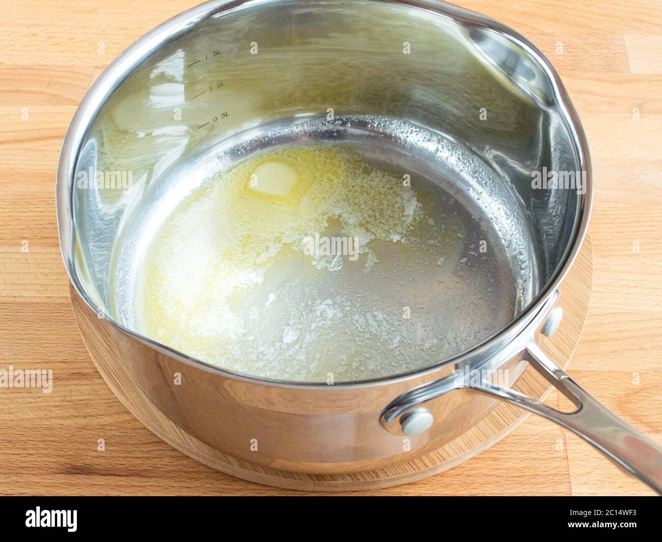 Butter is melted in a ladle. Yellow butter at the bottom of the pan