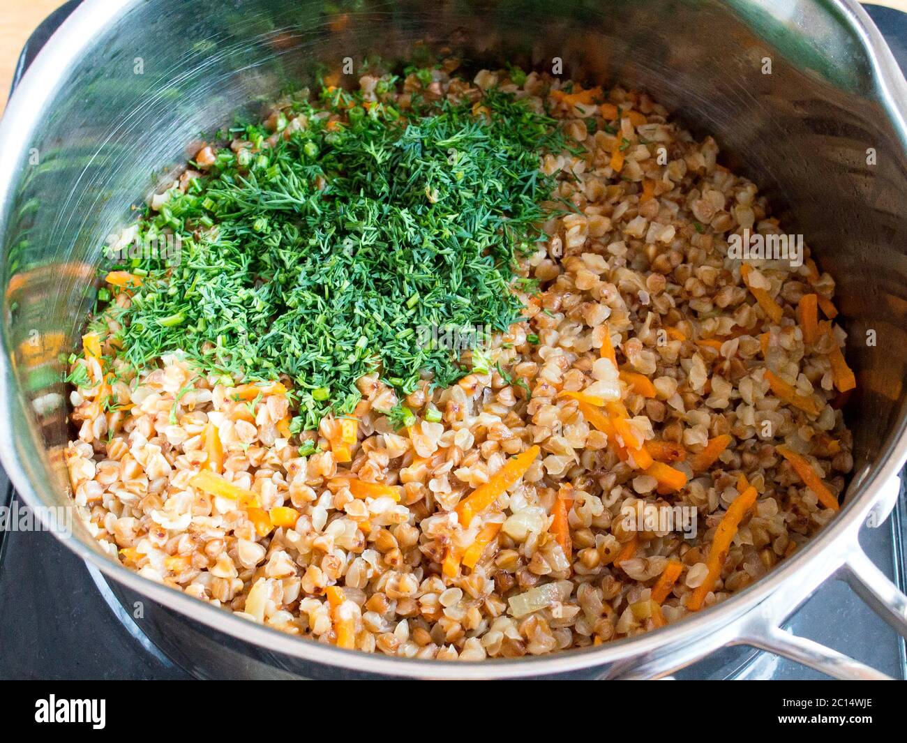 Add finely chopped greens to buckwheat with vegetables. Cook porridge with vegetables. Stock Photo