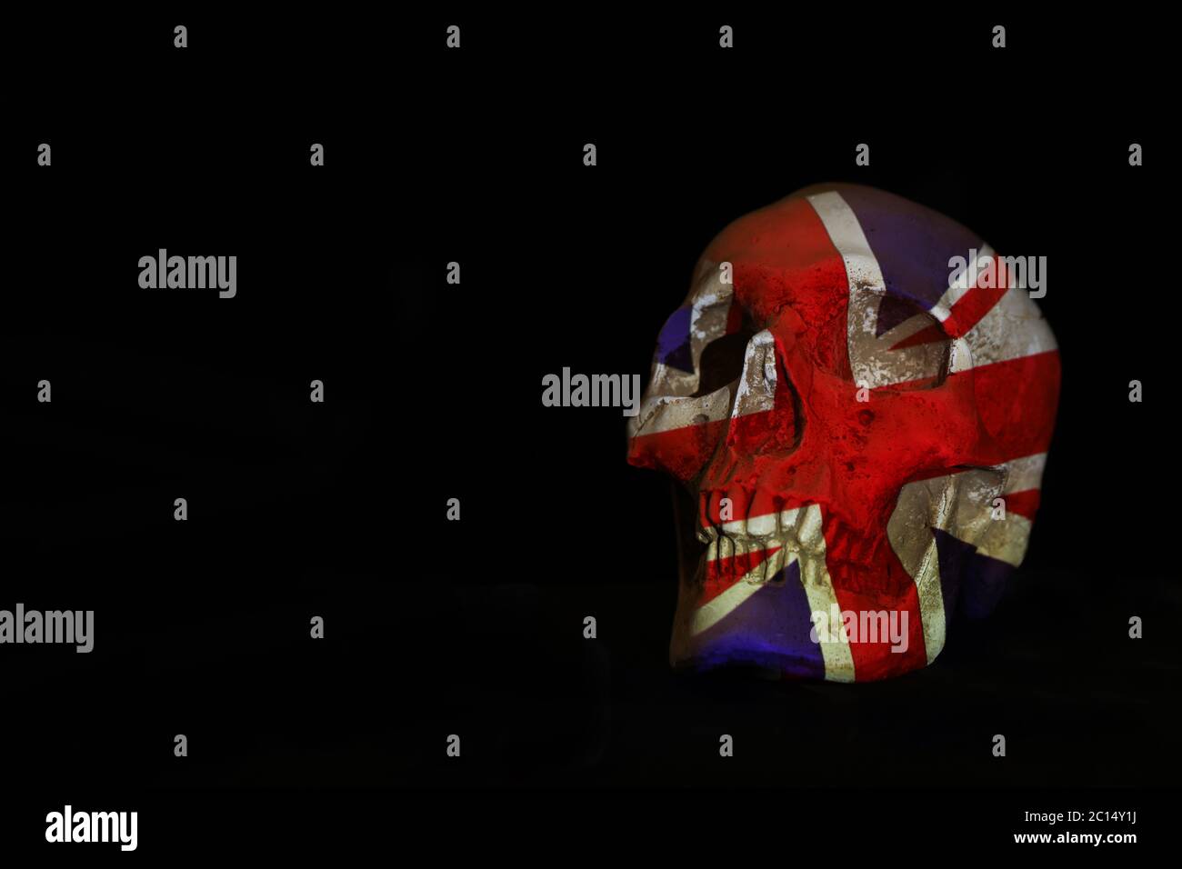 An isolated white skull set against a plain black background with the Union Jack or British flag projected over it. Stock Photo