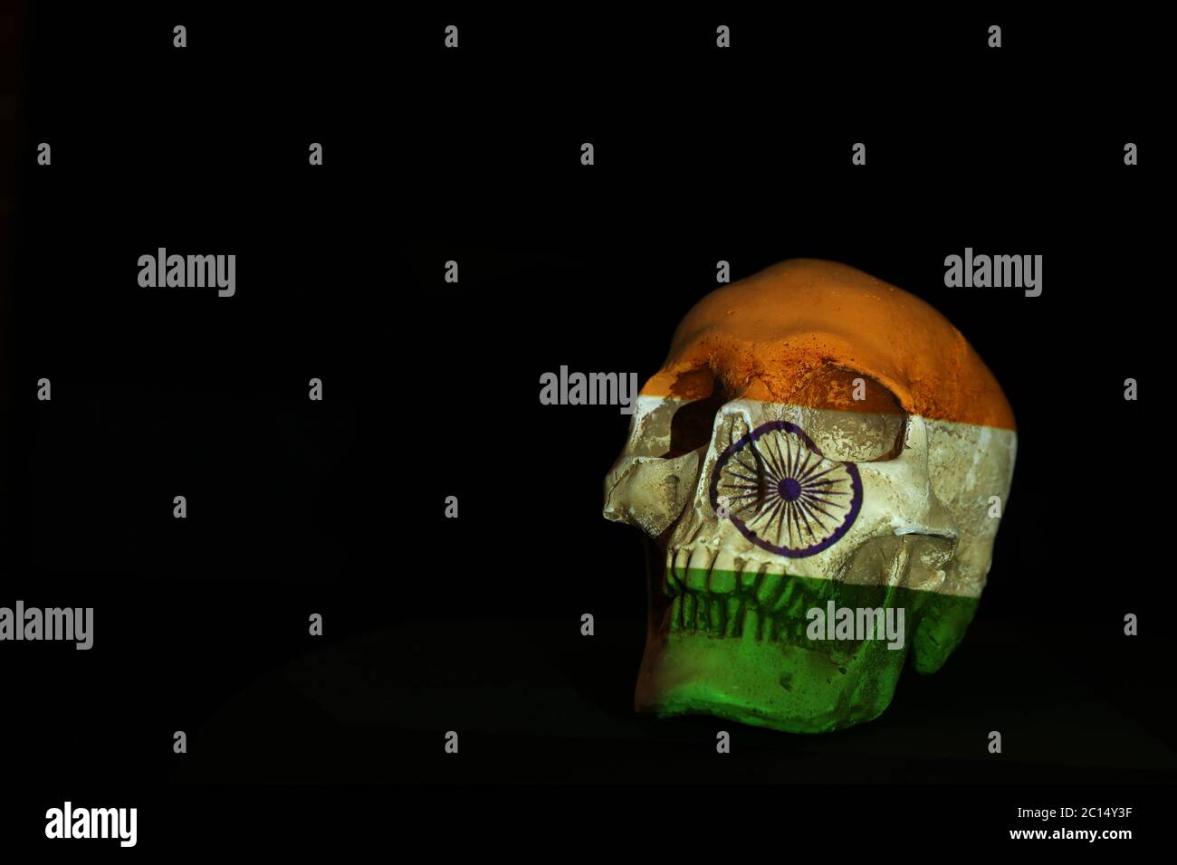 An isolated skull against a black background with the Indian flag projected or draped over it. Stock Photo
