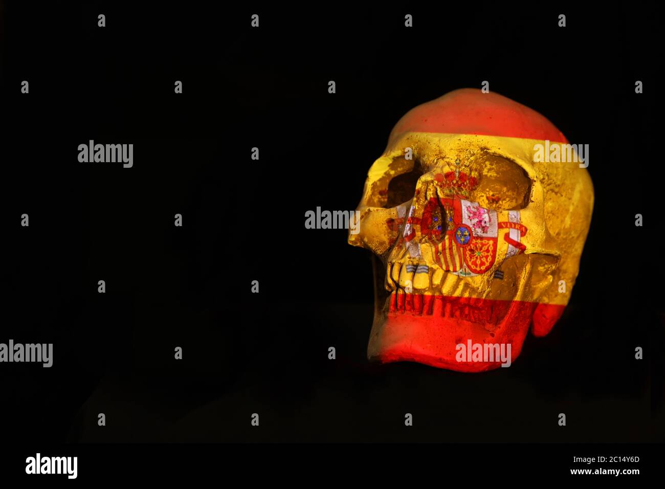 Spanish national flag projected over an isolated skull set against a plain black background Stock Photo
