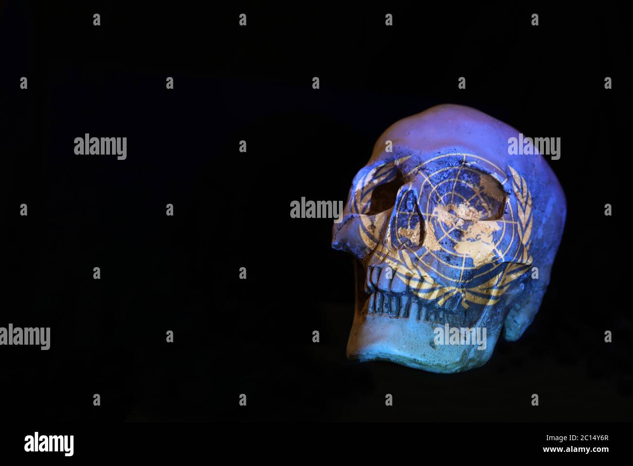 The United Nations UN symbol logo projected over a skull isolated against a plain black background. Stock Photo