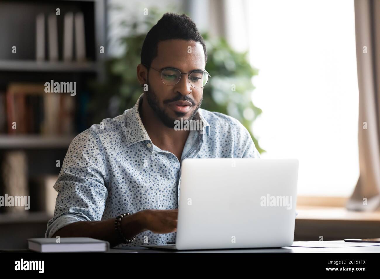 African man sitting at desk using laptop do remote work Stock Photo