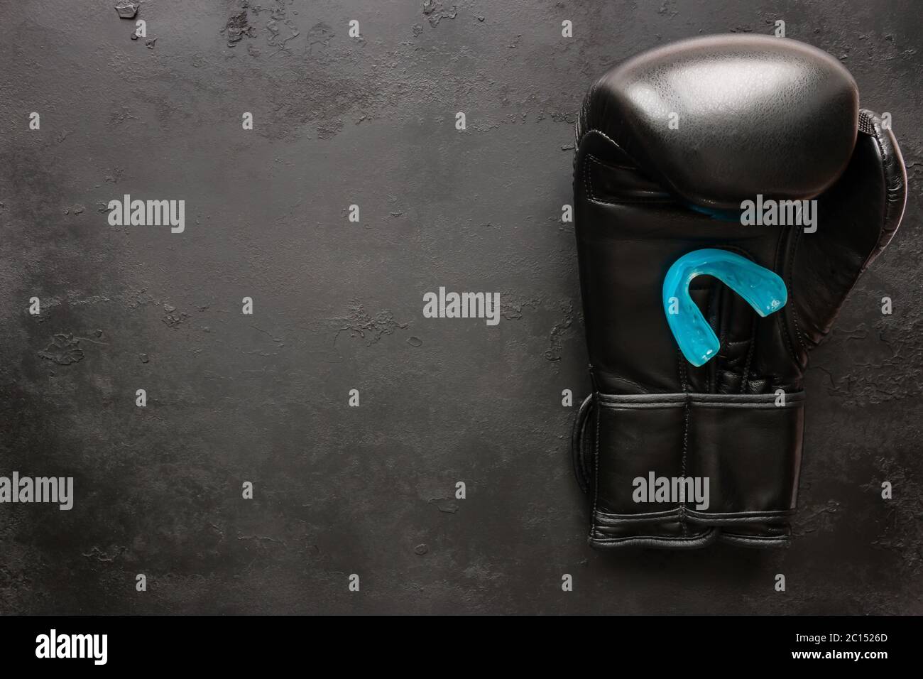 One boxing glove and a mouth guard on a black background with space for