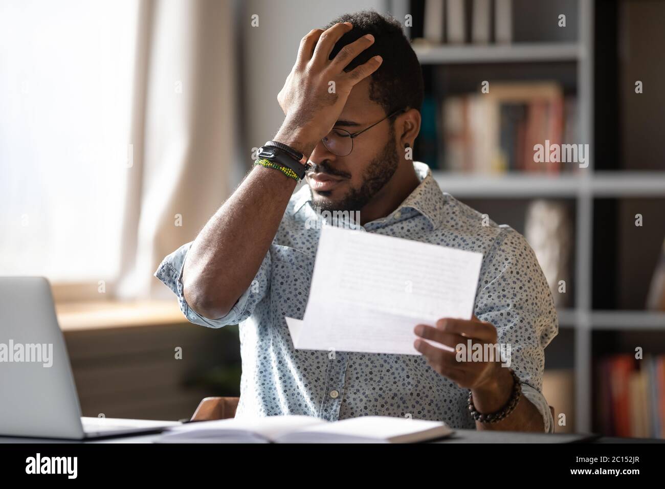 African businessman holding letter reading bad bank news about debt Stock Photo