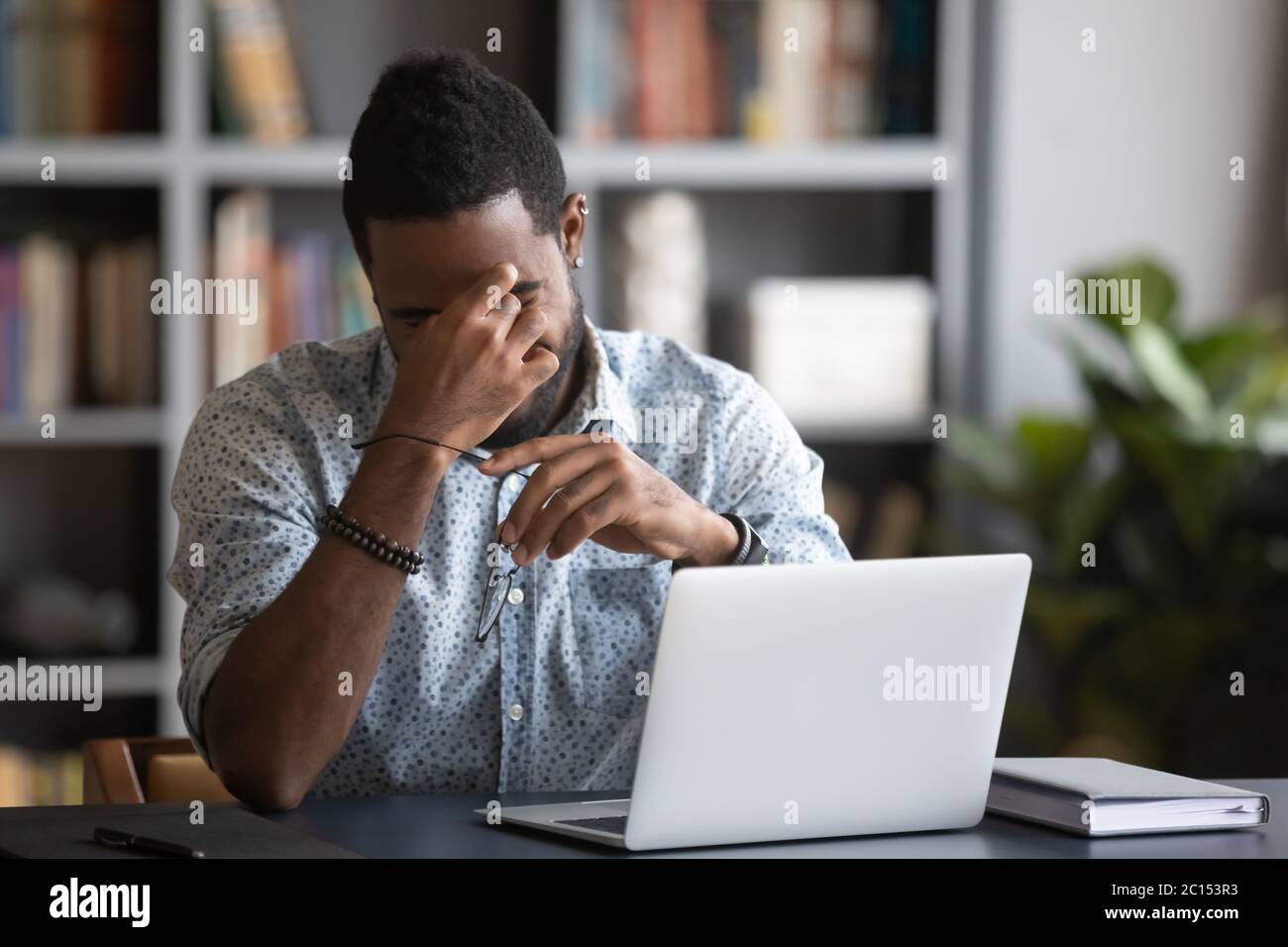 African guy rubbing dry eyes takes off spectacles relieving eyestrain Stock Photo