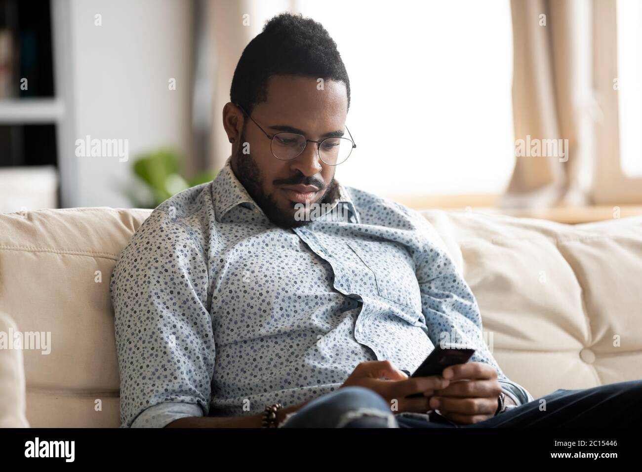 Absorbed african guy read internet news using smartphone at home Stock Photo