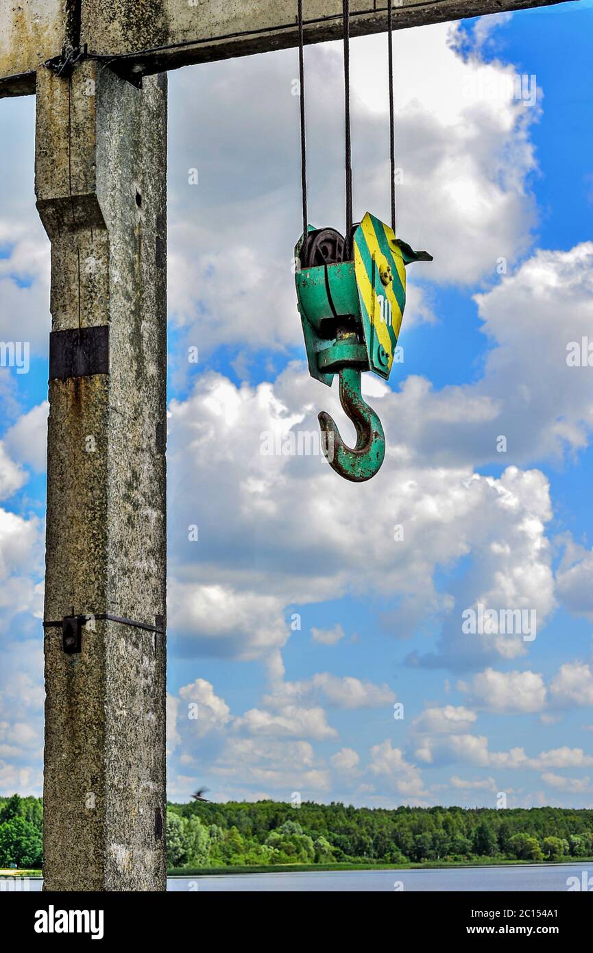 Yellow-green hook of a construction crane on a rope on a background of clouds Stock Photo