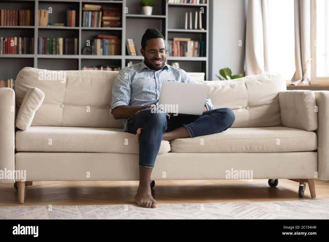 African guy rest on sofa using notebook watching movie Stock Photo