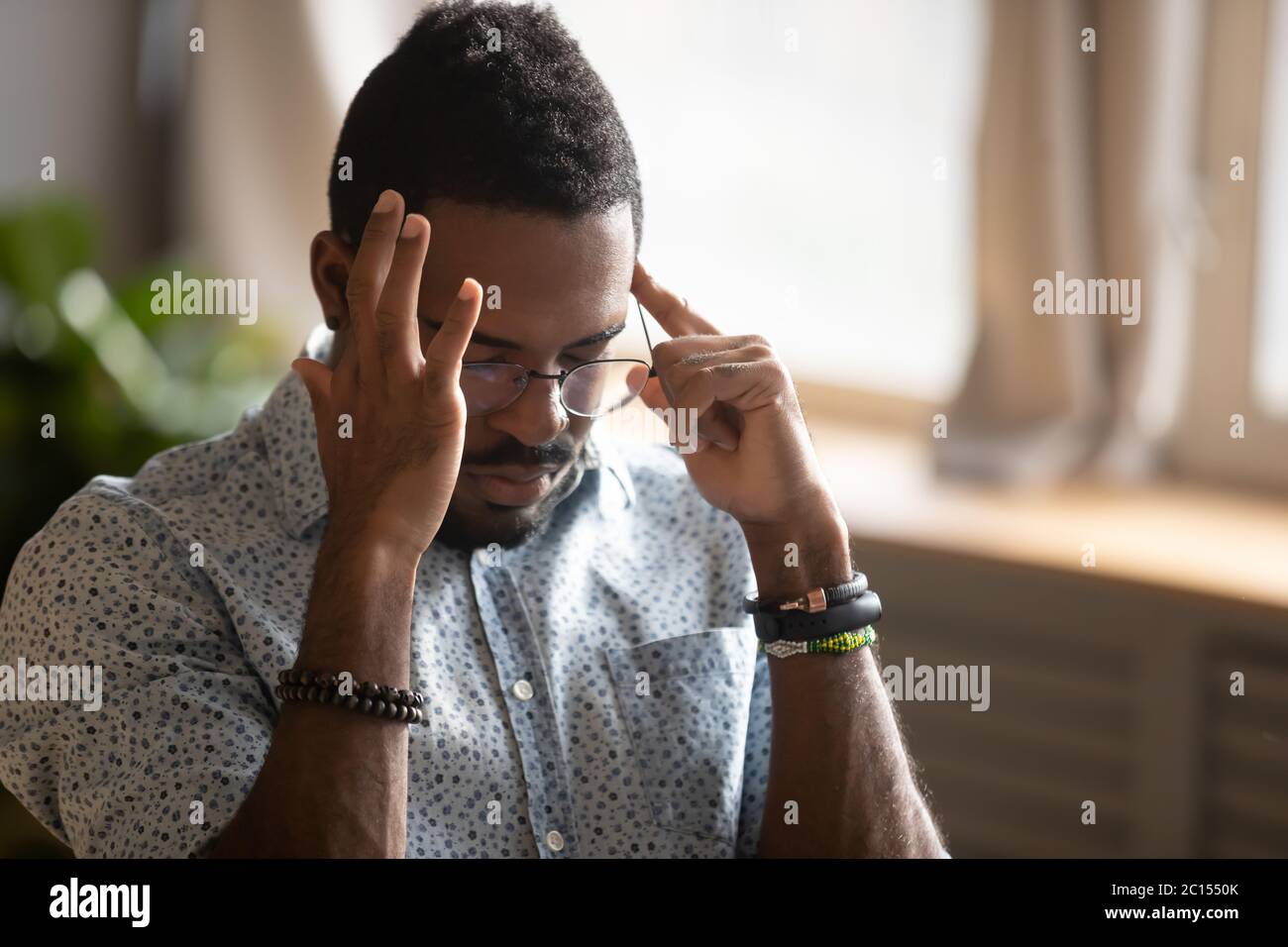 African guy closed eyes massaging temples suffers from migraine Stock Photo
