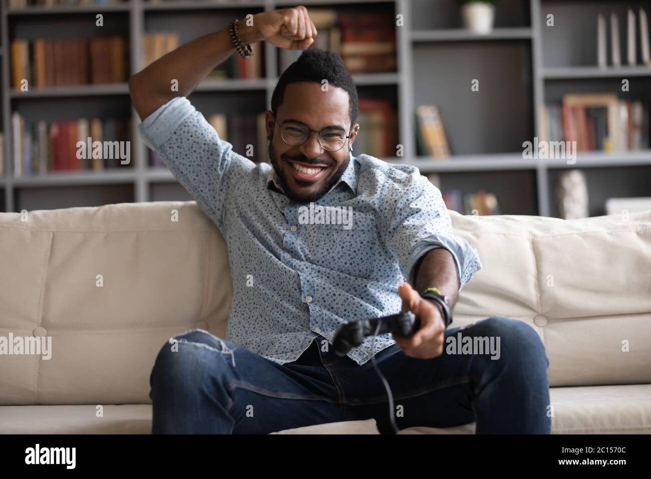 Excited African guy holding joypad celebrating victory in playstation games Stock Photo