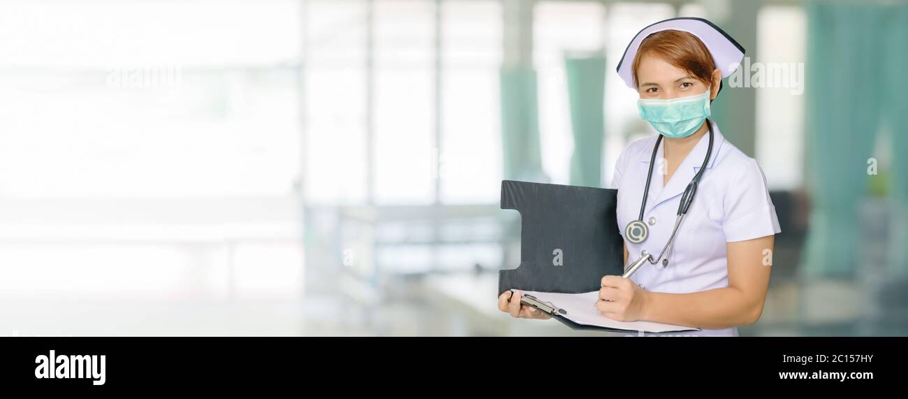 Asian female nurse writing medical report on Ward bed Hospital Blurred background for wide banner background design Stock Photo