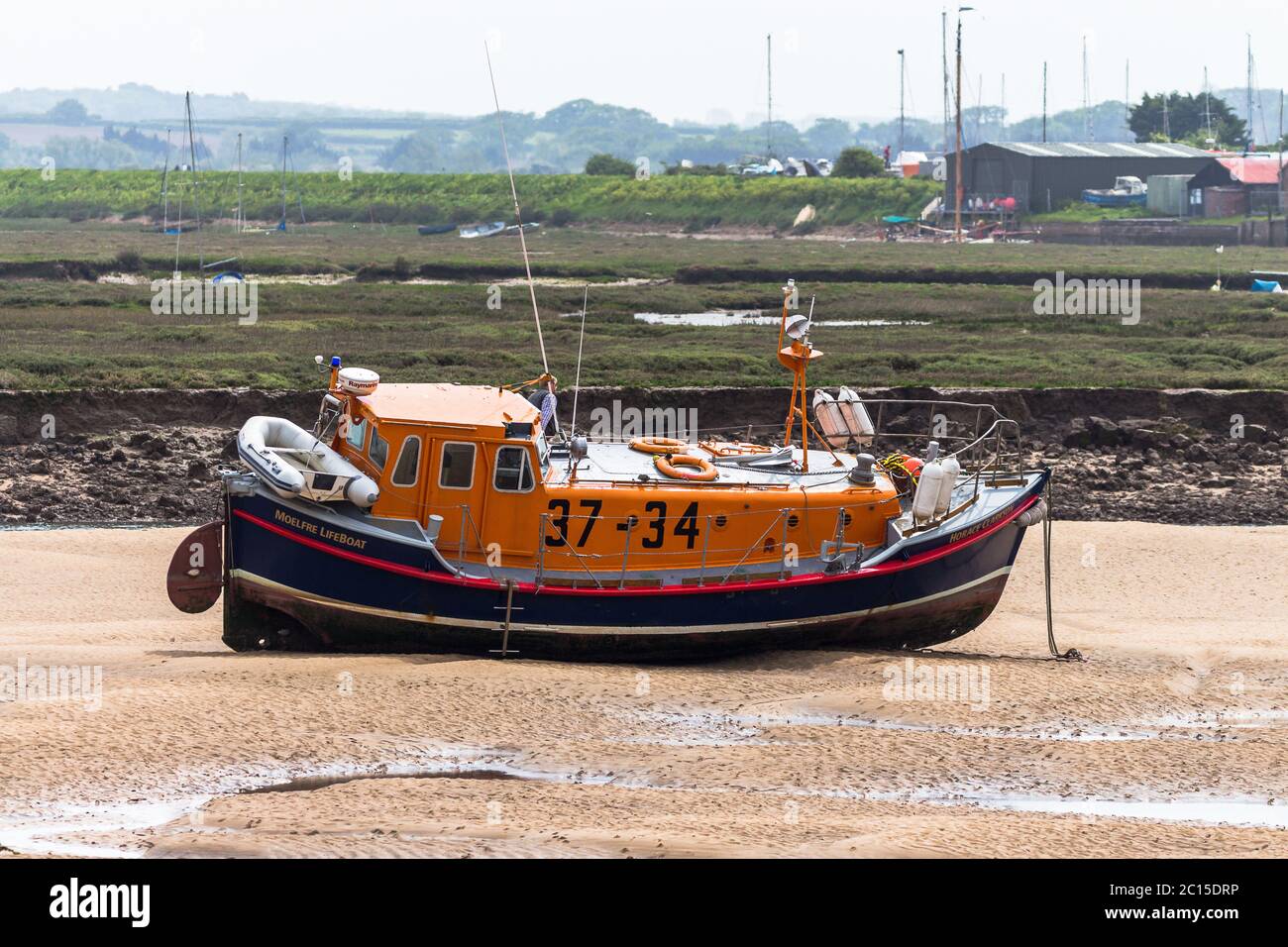 Lifeboat sitting on the mud flaps waiting to refloat on the tide. Stock Photo