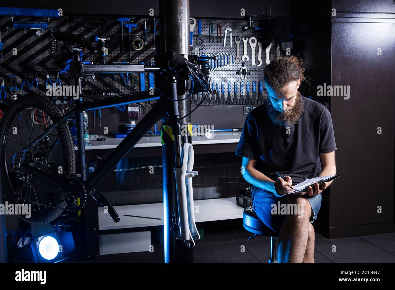 Stylish man with beard, cycle mechanic takes notes, checklist before ...