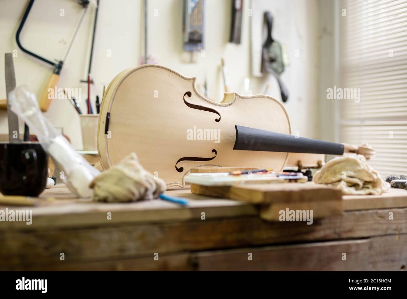 An off-white violin, ready for restringing, sat on a crafting bench after being sanded down and varnished in a work shop in Cheltenham. Stock Photo