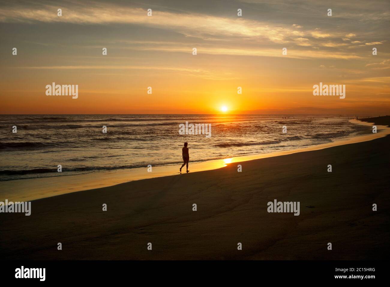 Silhouette of a woman walking on beach during sunset. El Paredón, Pacific coast, Guatemala Stock Photo