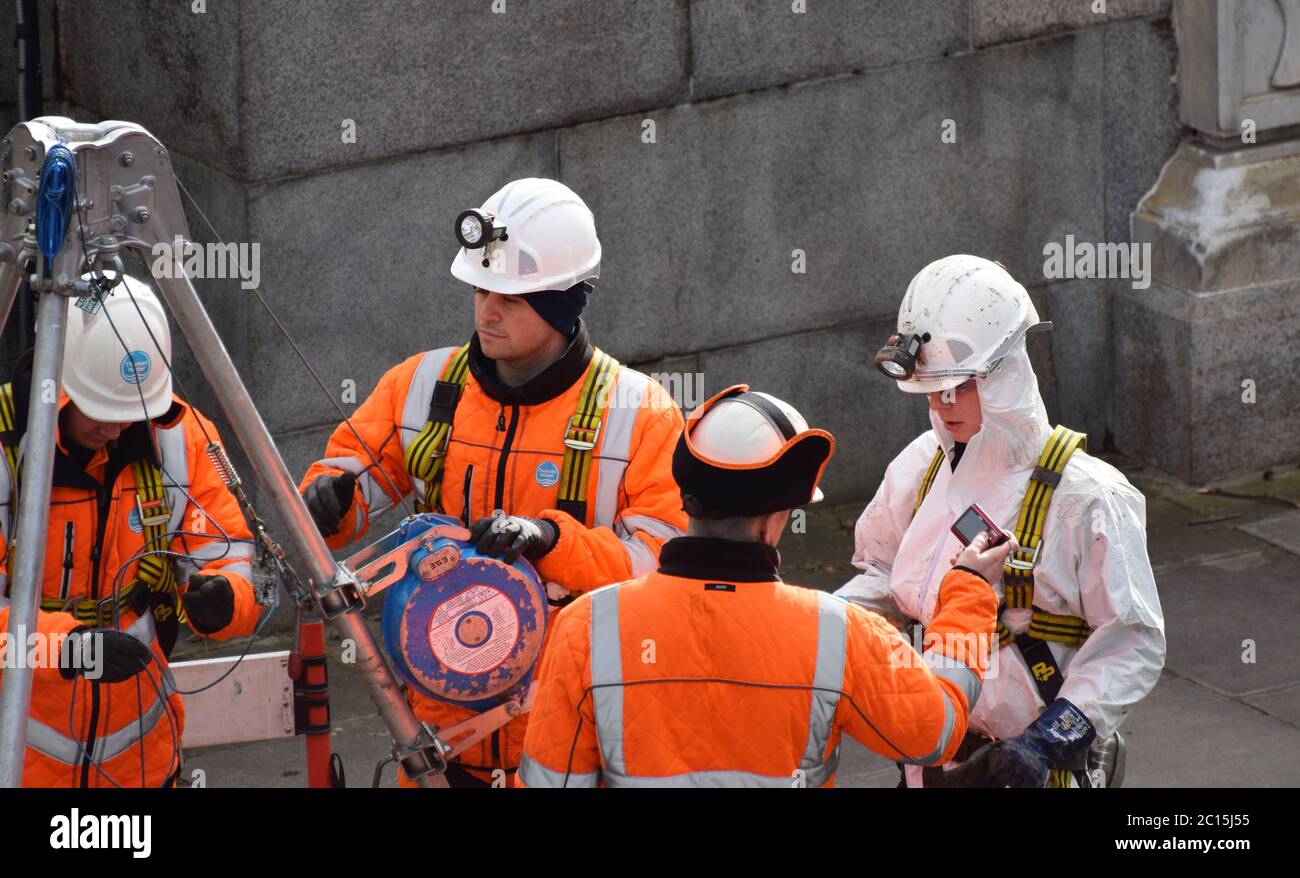 4 Specialist engineers working on something deep in the ground in the centre of London next to the river Thames. 3 men and 1 woman. Stock Photo
