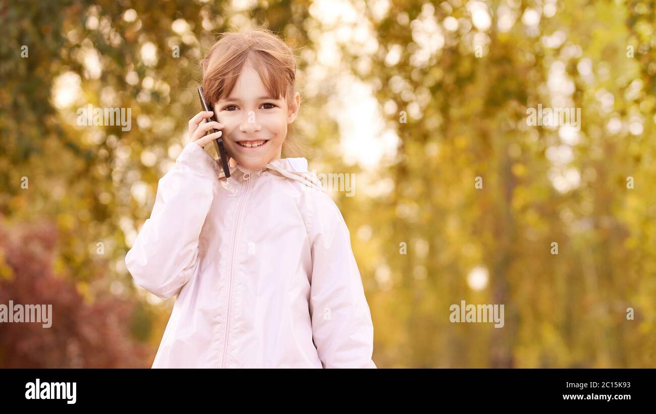Little girl talk phone. Autumn background Stock Photo