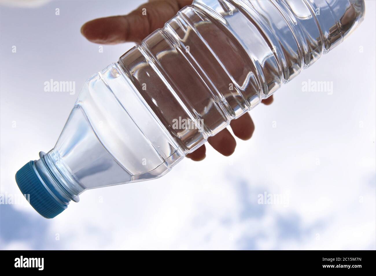 Hand taking fresh water bottle on sky background Stock Photo