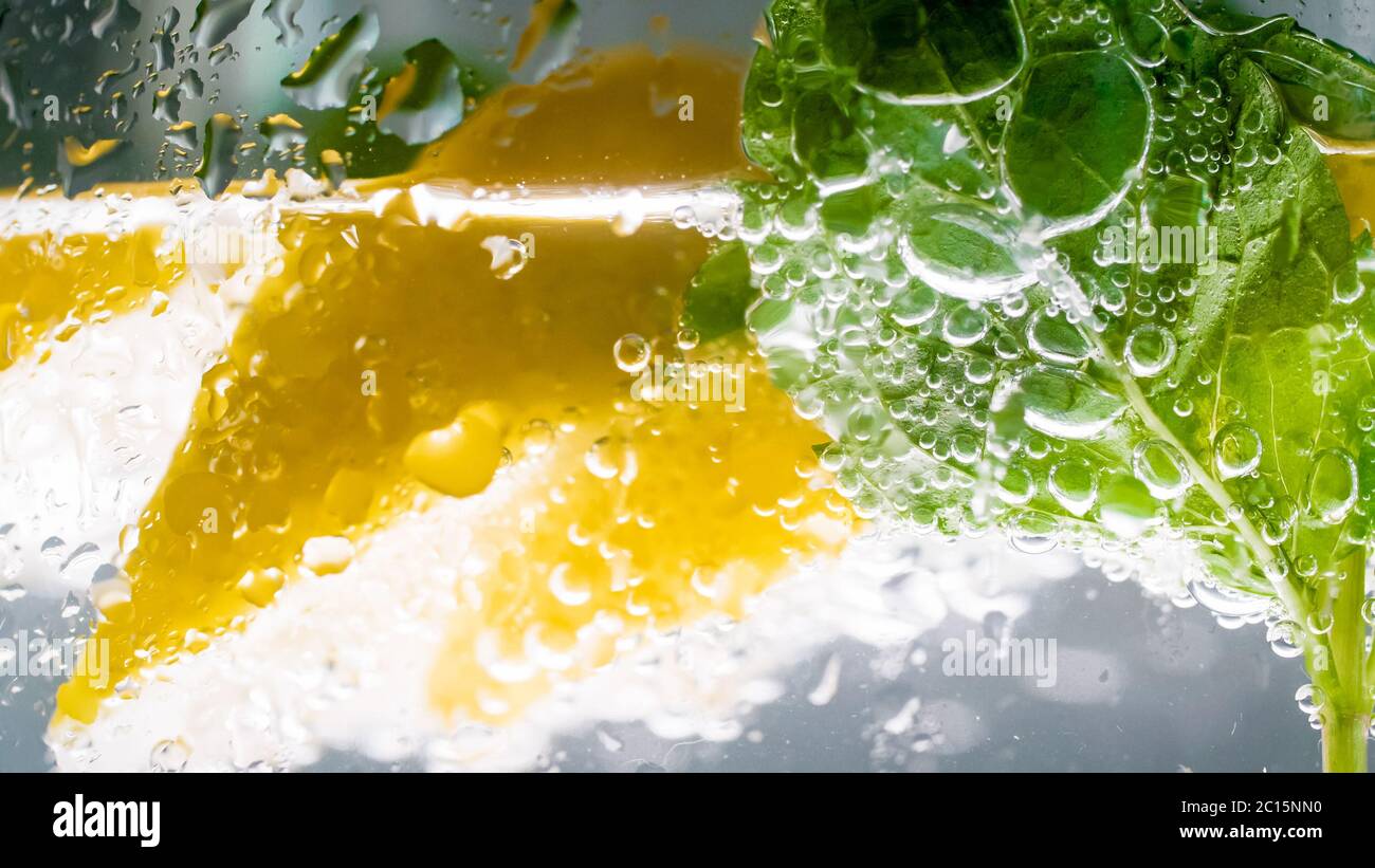 Macro image of air bubbles, ice cubes, mint leaves and lemon slice in