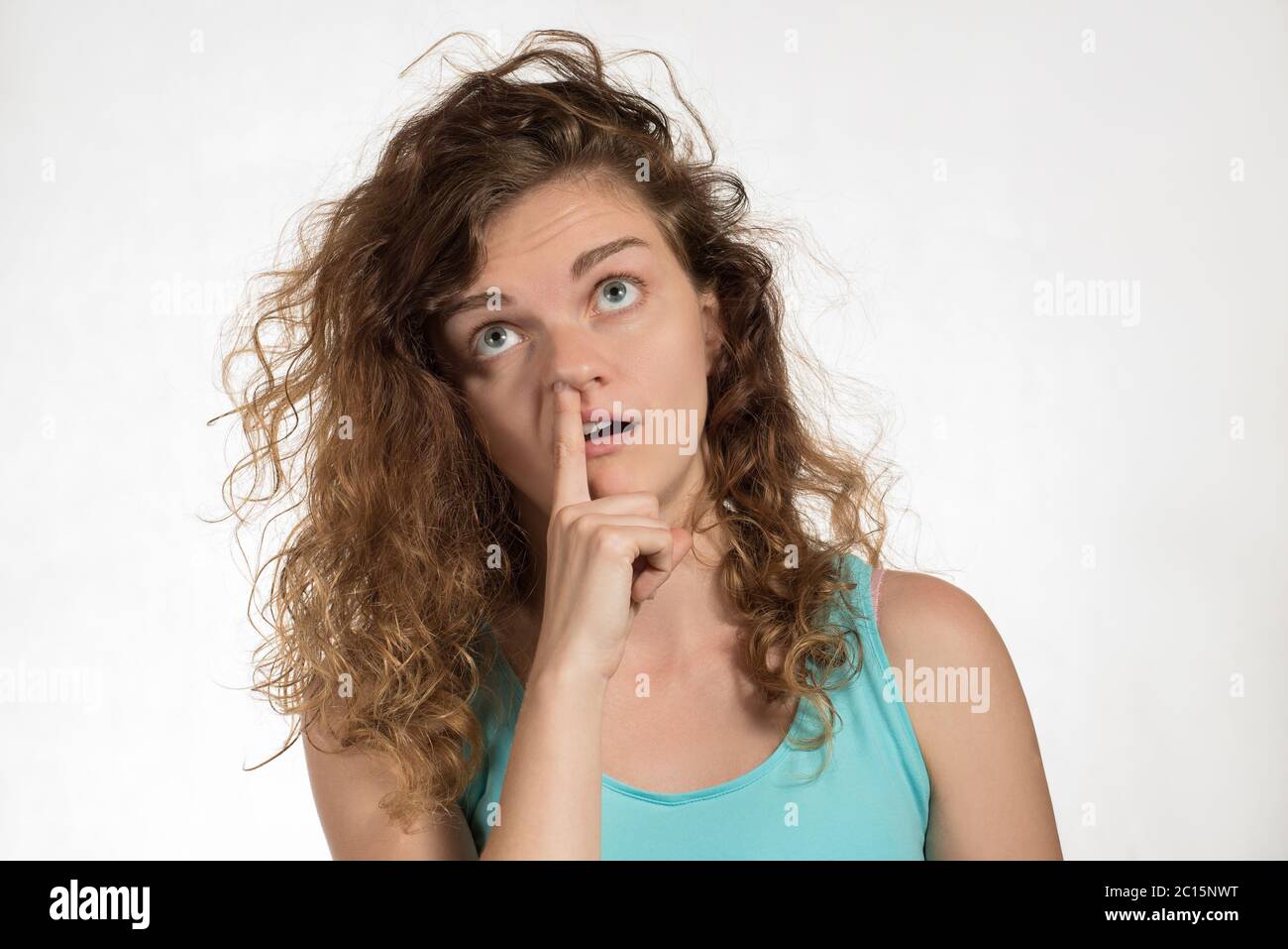 Beautiful brunette girl picking at her nose and her stupid face on a white background Stock Photo