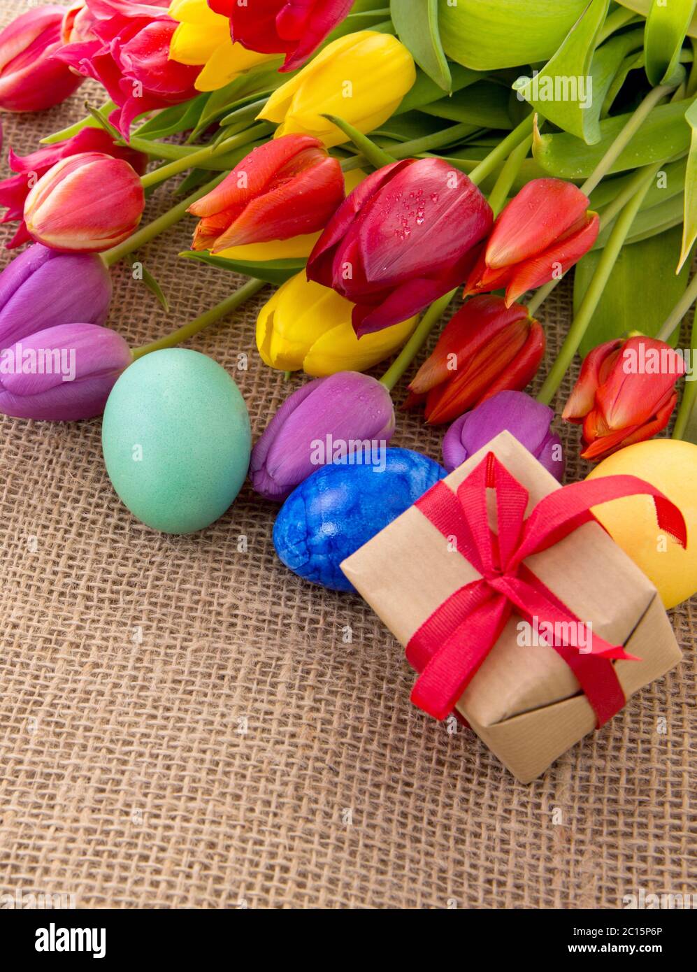 Spring tulips with colorful easter eggs and gift box. Stock Photo