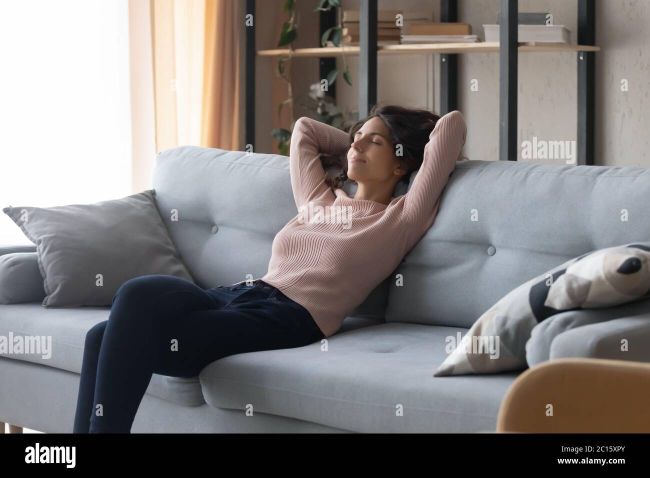 Relaxed satisfied young woman resting on cozy couch at home Stock Photo
