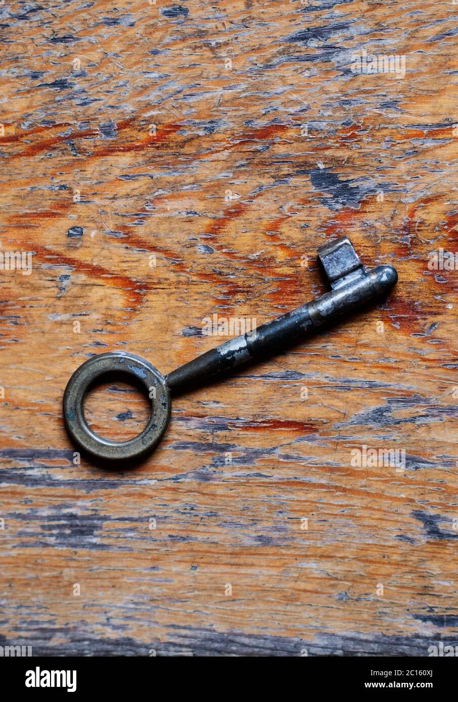 Old key on a worn out hardwood floor Stock Photo