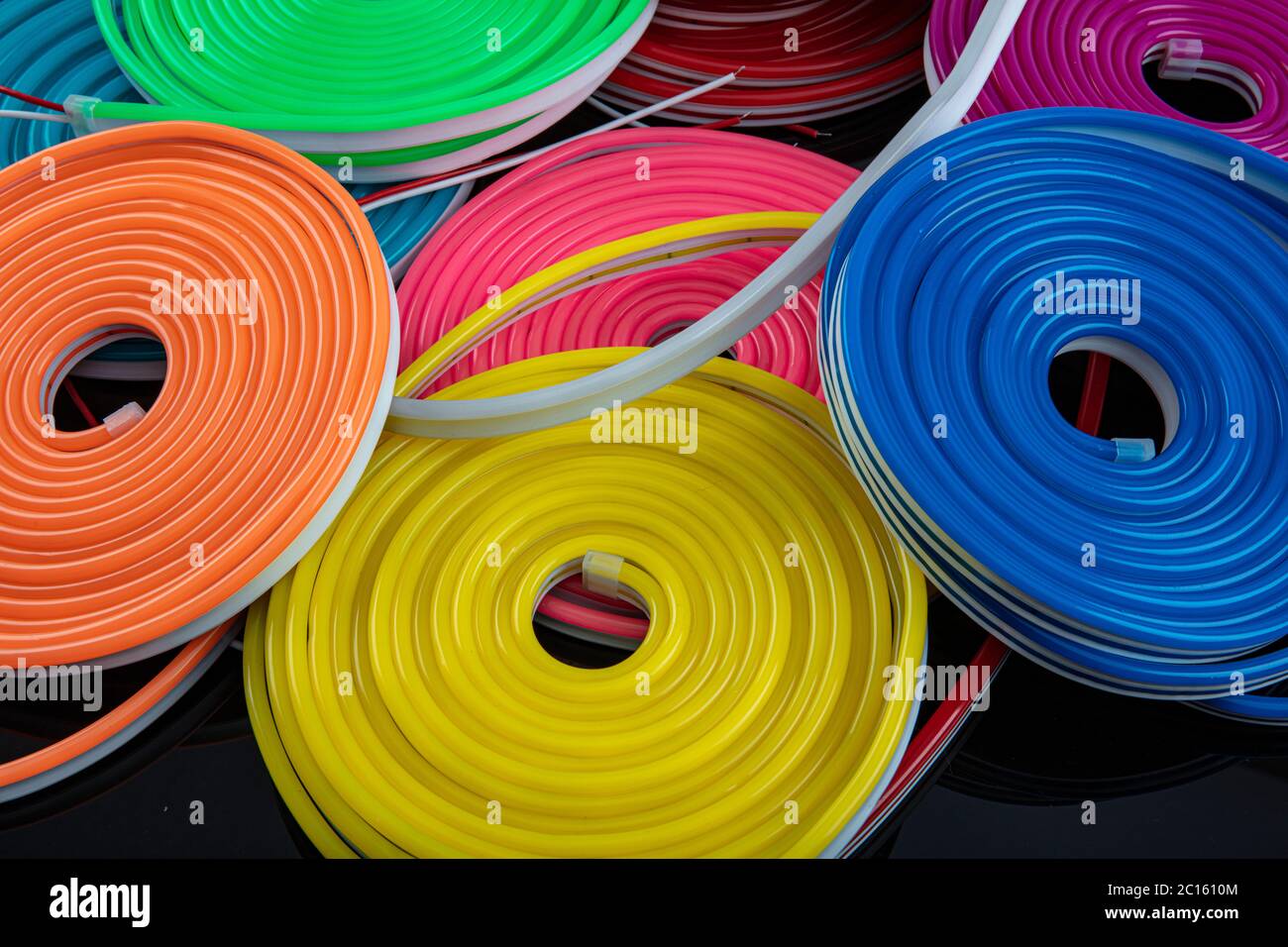 Neon flexible strip light. Flexible led tape neon flex in different colors on black background. Stock Photo