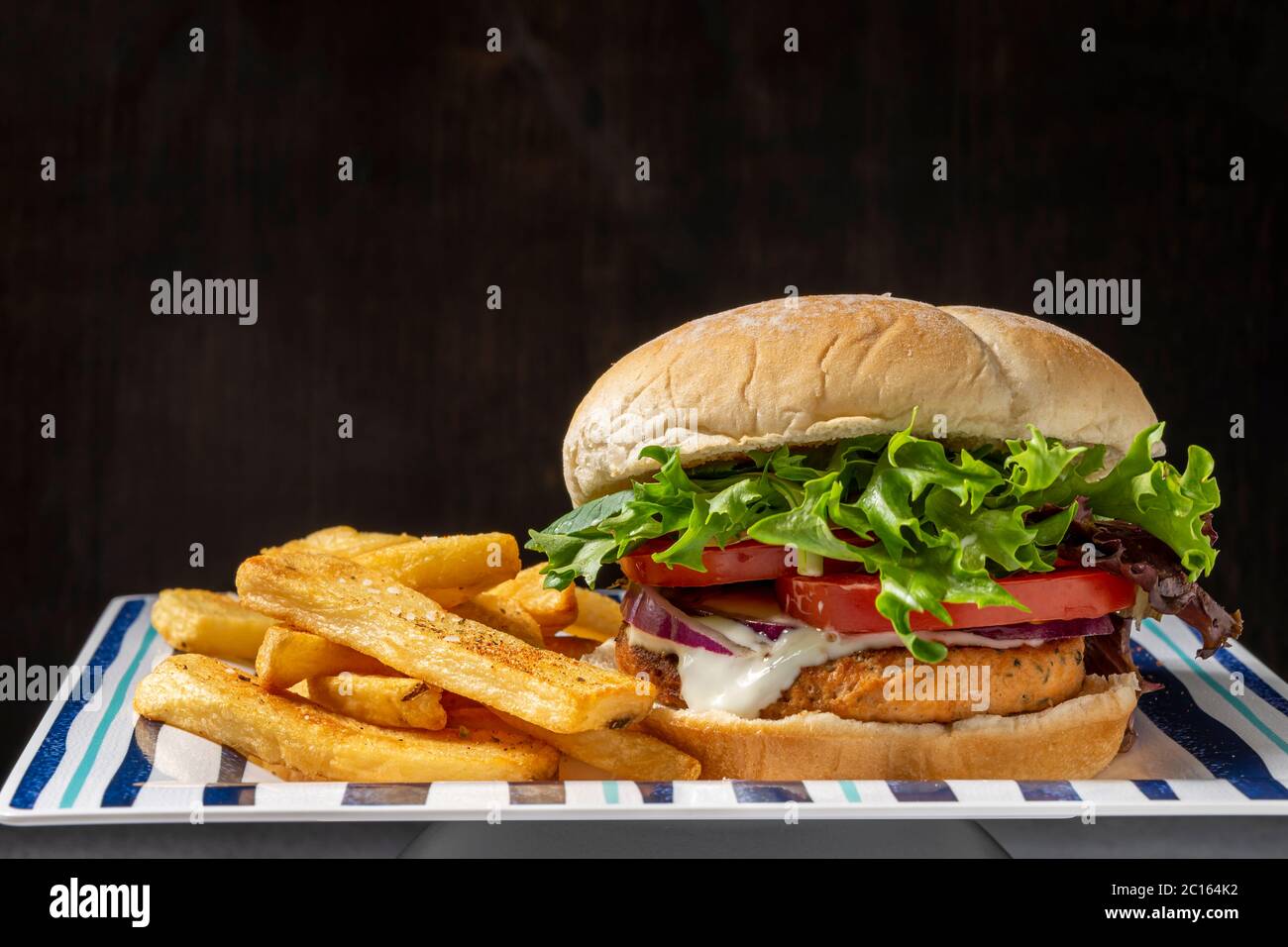 Salmonburger with home cooked oven baked fries Stock Photo Alamy