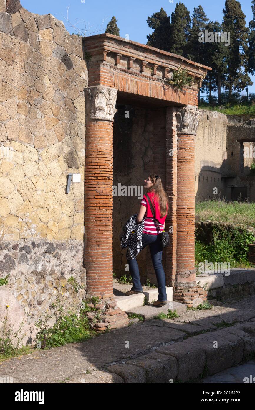 A tourist walks through the entrance to Casa del Gran Portale or House of the Large Portal on the Decumano Inferiore (Decumanus Inferior), Herculaneum Stock Photo