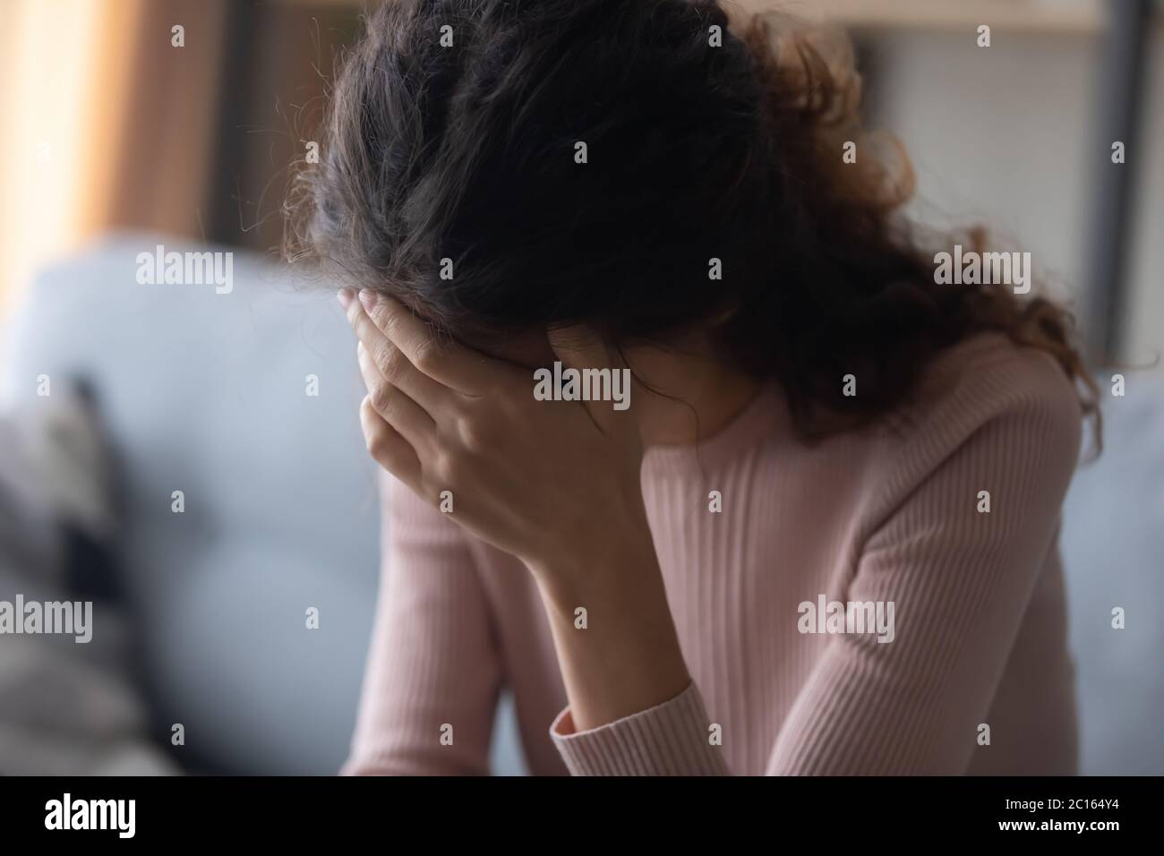 Close up frustrated depressed woman touching forehead, sitting alone Stock Photo
