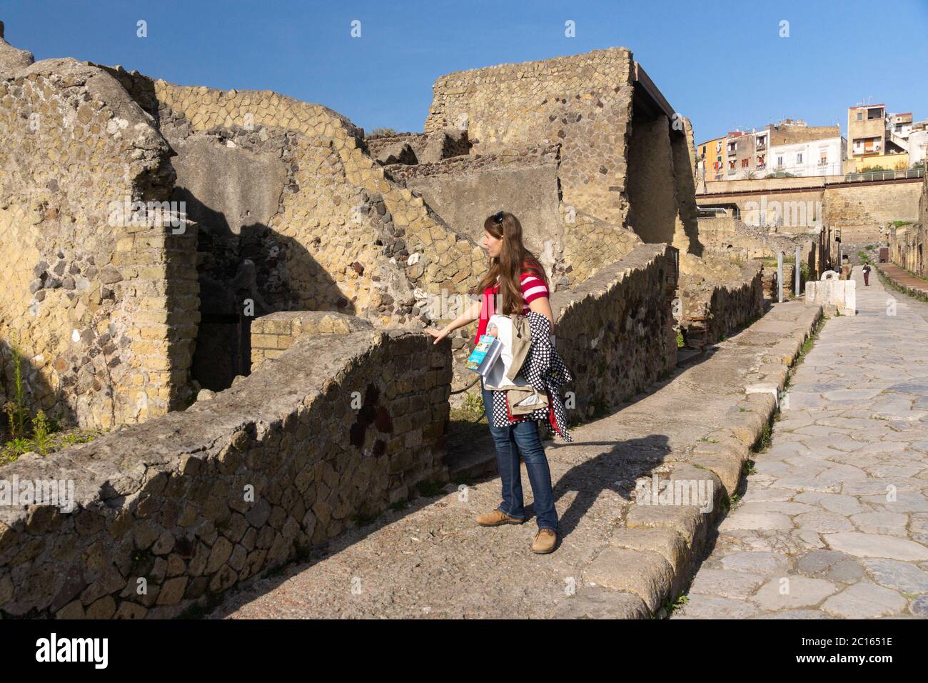 A female woman tourist on a footpath exploring the Cardo V Inferior (Inferiore) street in the ancient Roman UNESCO World Heritage city of Herculaneum Stock Photo