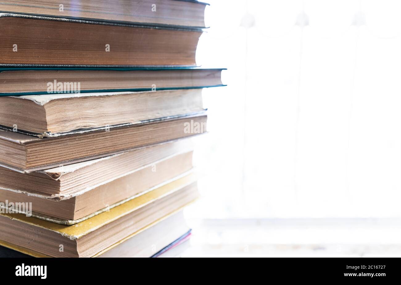 A stack of old books lying on a windowsill Stock Photo