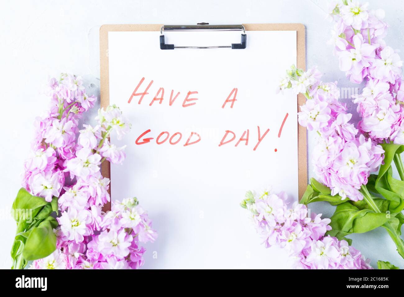 Light white Desk top view. Phrase words Have A Good Day. Purple flowers and lap top top view, flat lay. Good morning.  Stock Photo