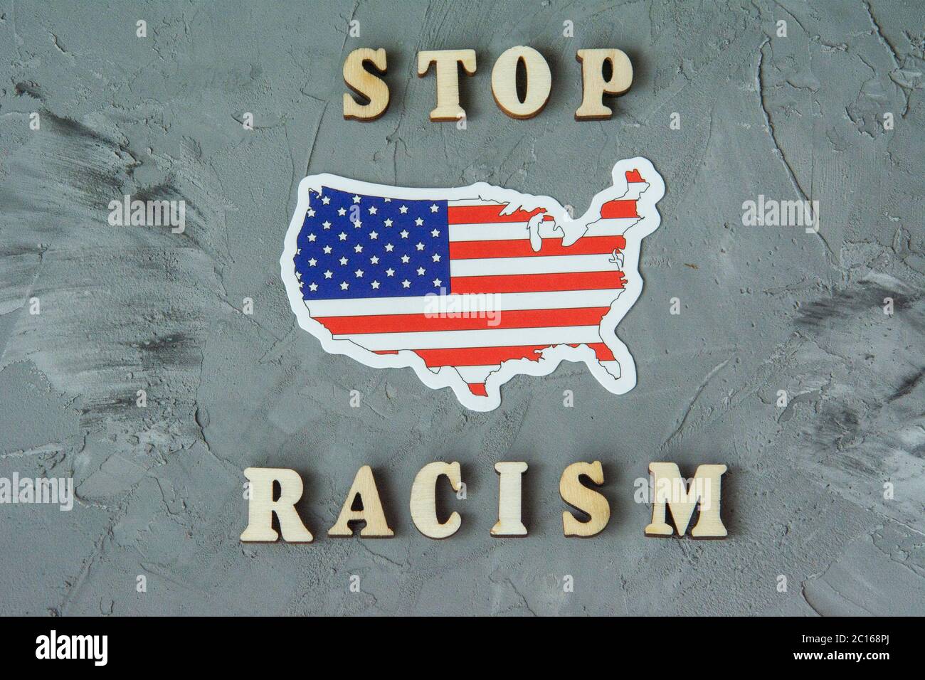 Stop racism sign flat lay on a gray background with american flag. Concept of racism. Discrimination, racial problems. Stock Photo