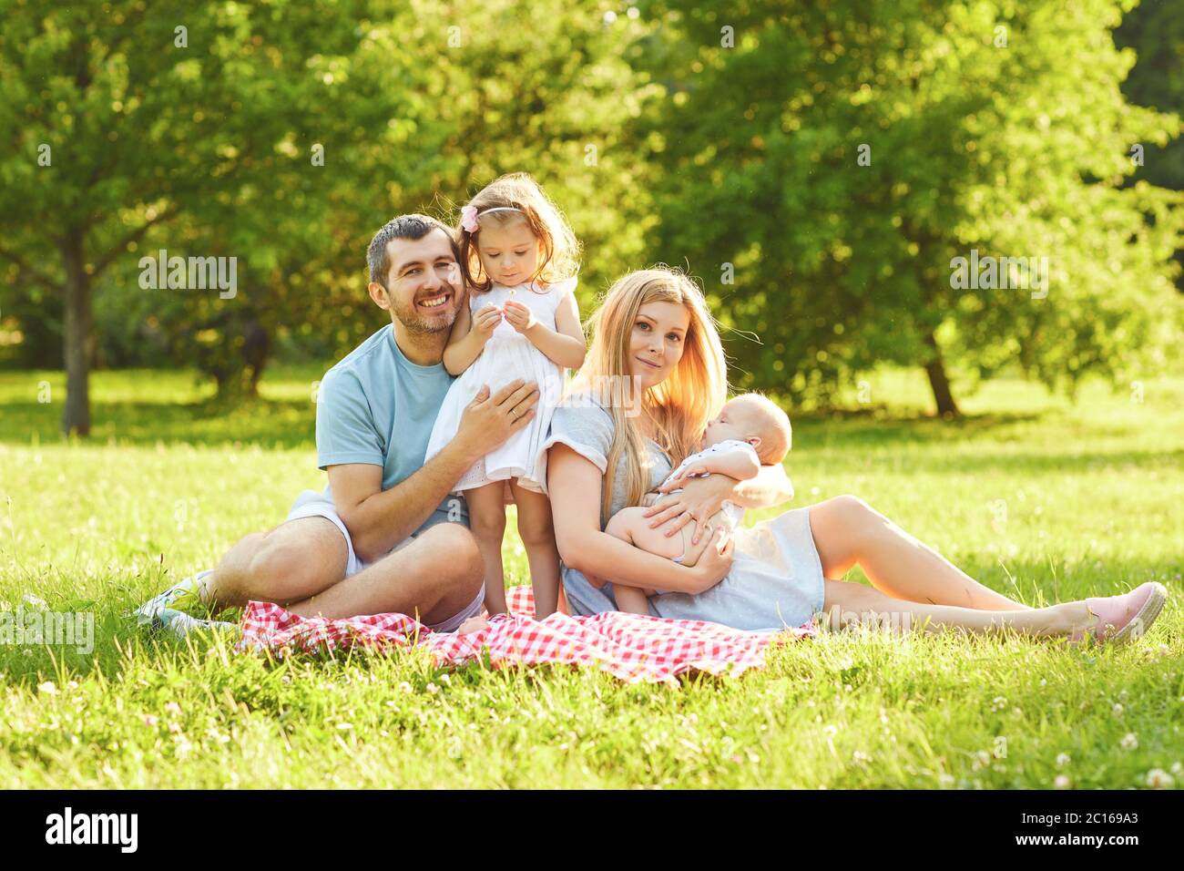 Happy family sitting on the green grass are playing in the park Stock ...