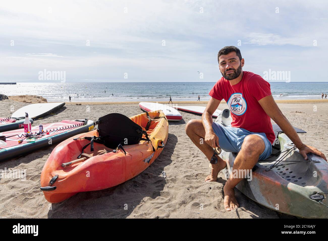 Local residents have the beach to themselves as the weather hots up for summer. Owner at Red Rock Surf prepares kayaks for hire. Phase 3 de-escalation Stock Photo