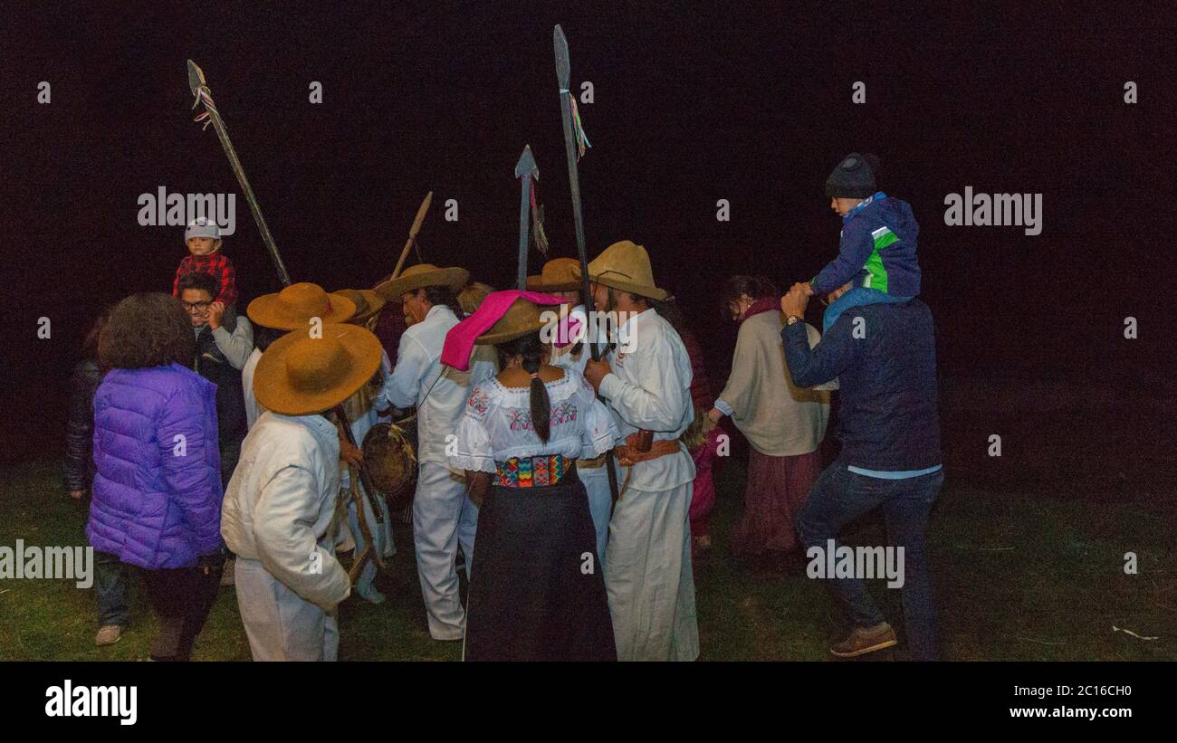 Quito, Pichincha / Ecuador - February 16 2019: Indigenous woman dressed in typical costume and indigenous men dancing in a circle with tourists on a b Stock Photo