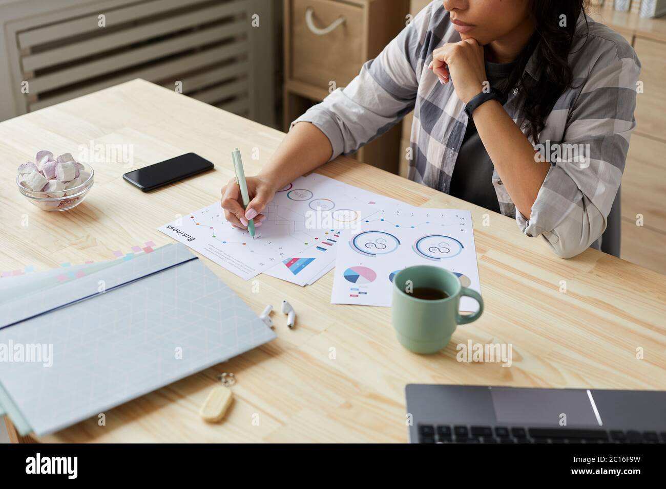 Cropped portrait of young mixed-race woman drawing graphs and charts while planning project at home office, copy space Stock Photo