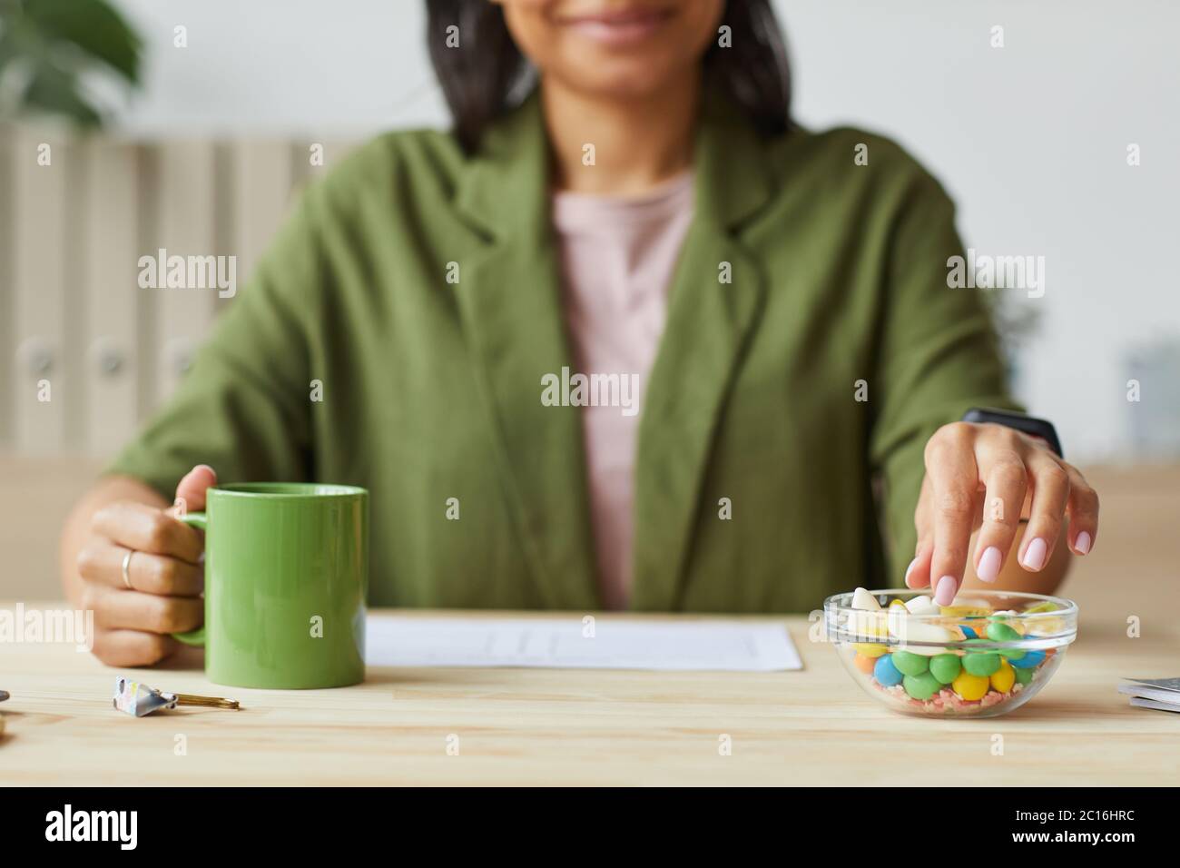 Cropped portrait of mixed-race young woman enjoying sweet gummy snacks while working from home, copy space Stock Photo